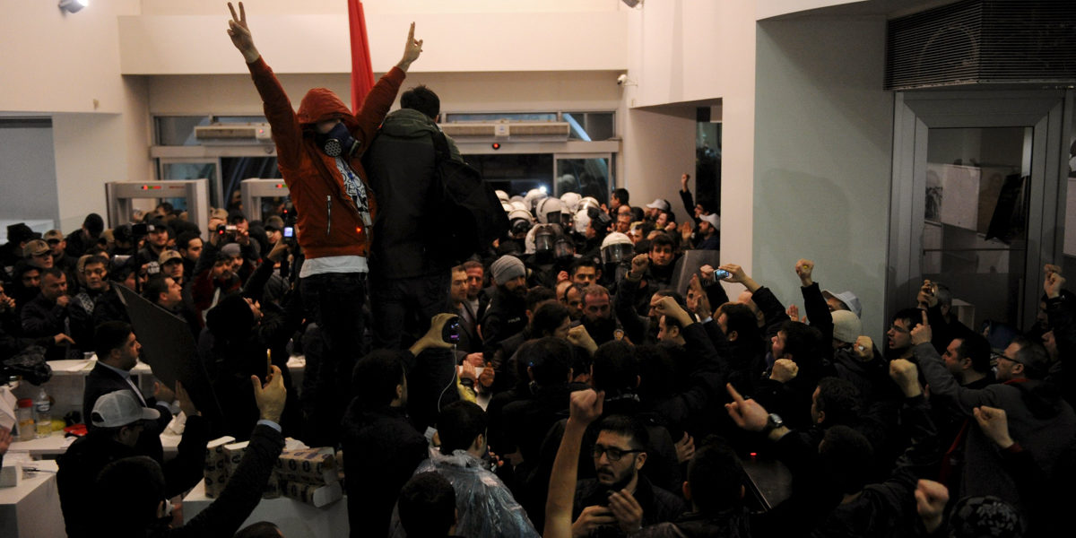 Employees react as riot police enter the headquarters of Zaman newspaper in Istanbul