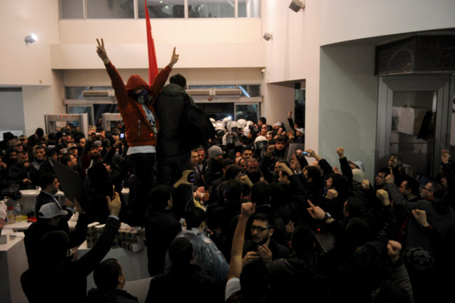 Employees react as riot police enter the headquarters of Zaman newspaper in Istanbul